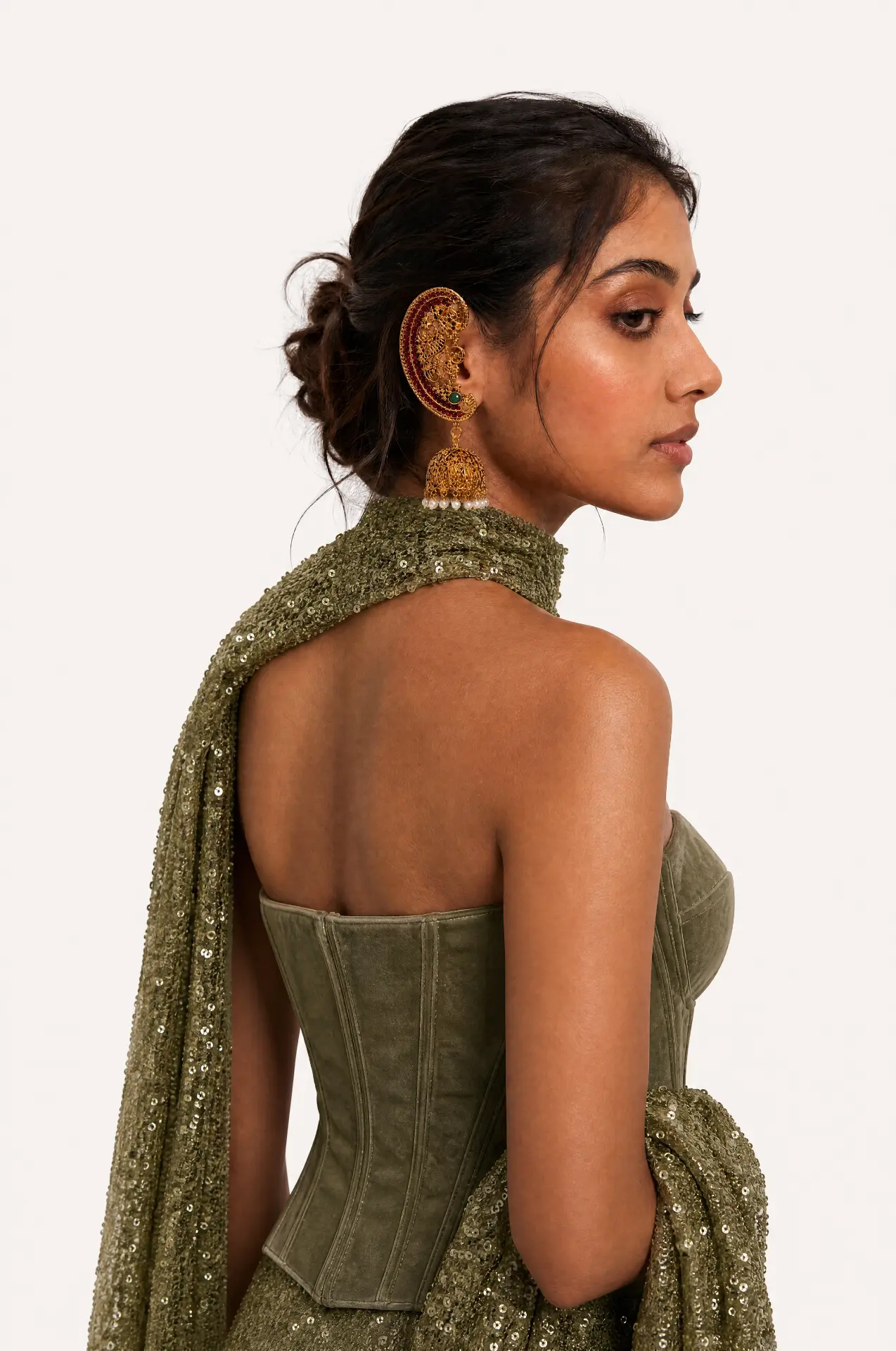 Model in olive corset and sequin drape wearing a gold ear cuff with jhumka